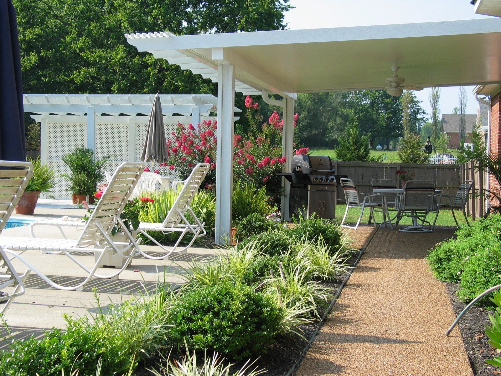 A patio with chairs and a grill under a pergola
