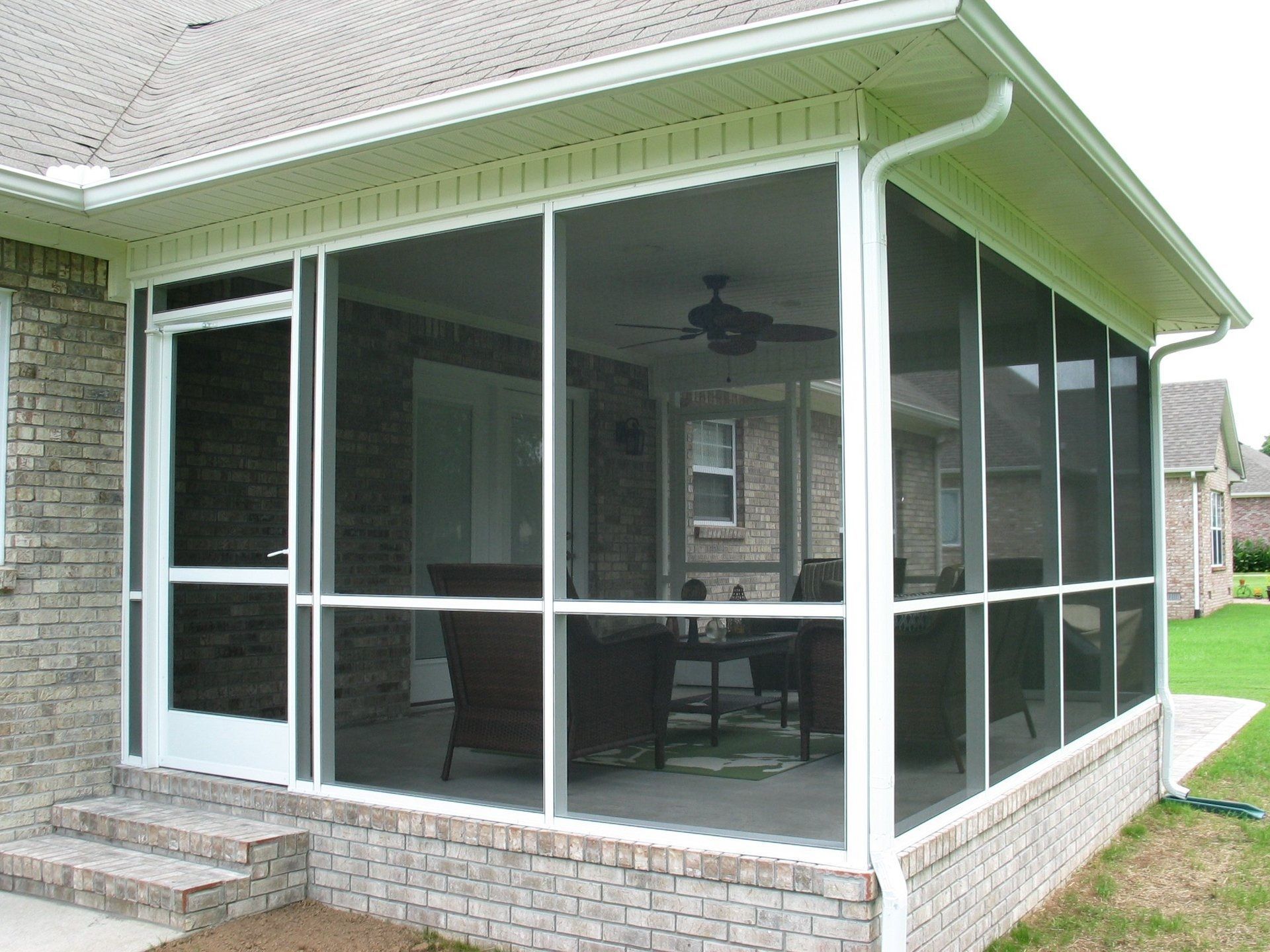 A screened in porch in front of a brick house