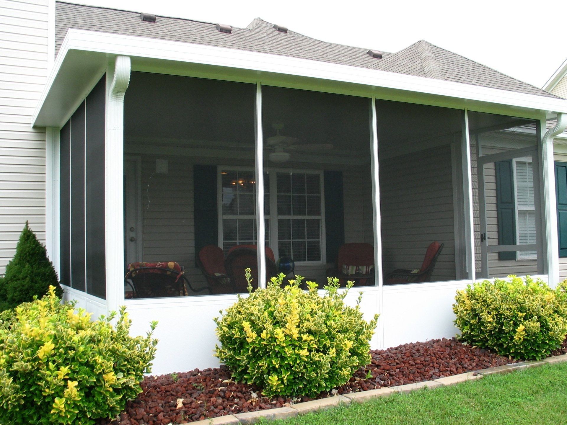 A screened in porch on the side of a house