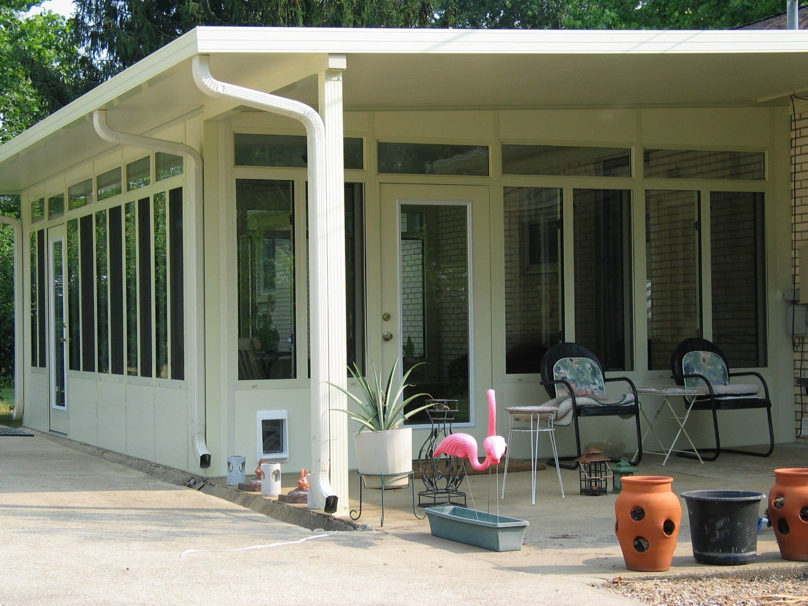 A white house with a pink flamingo on the porch