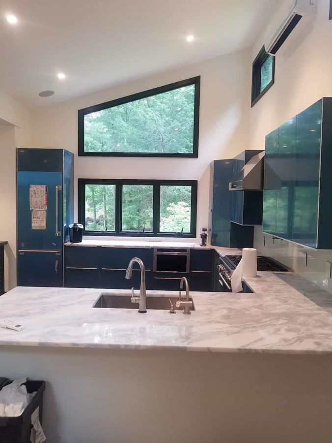A kitchen with blue cabinets and a marble counter top