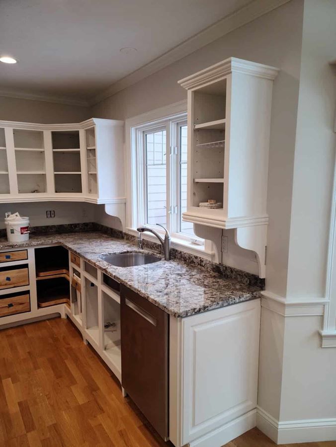 A kitchen with a sink , dishwasher , cabinets and a window.