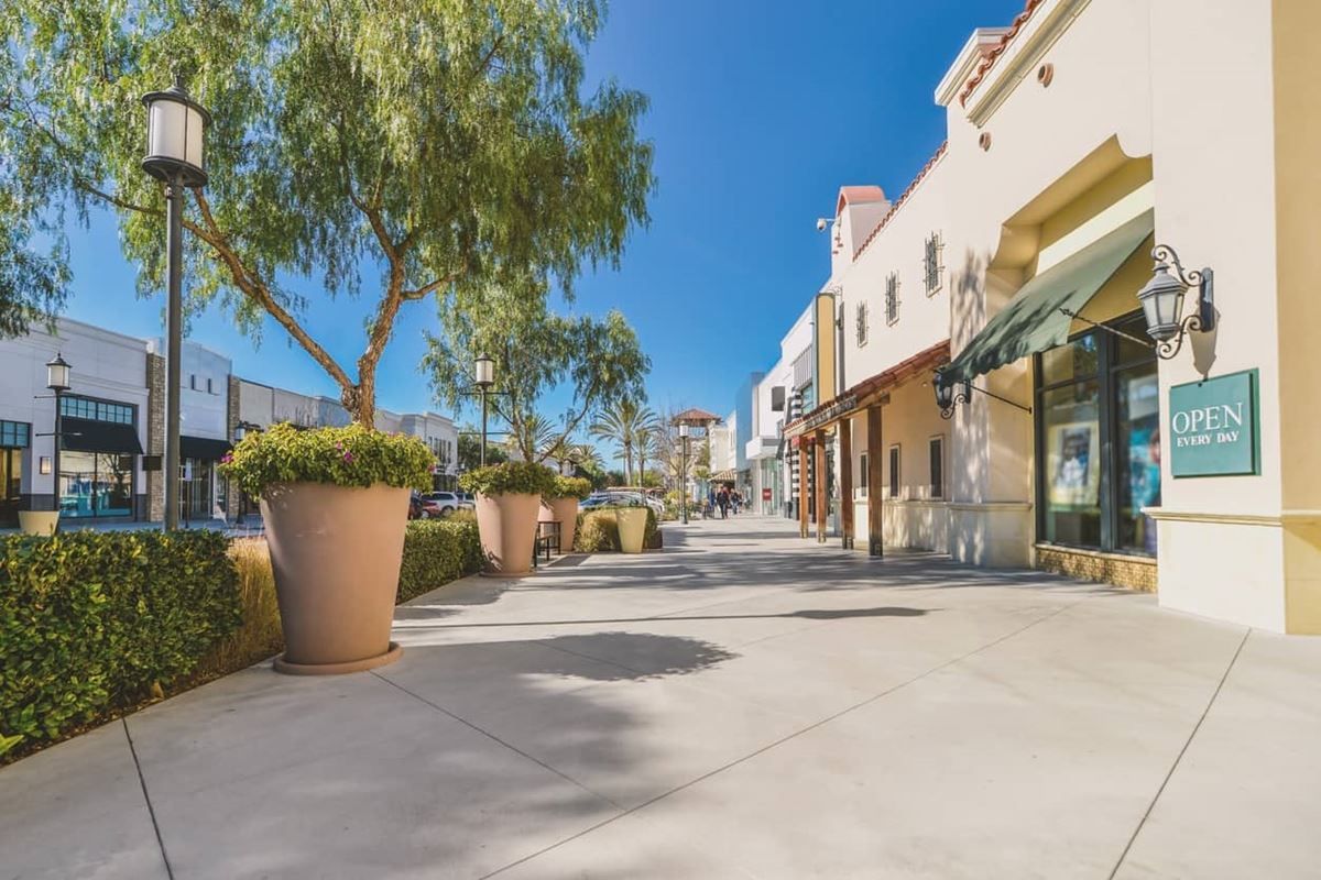 A row of stores are lined up on a sidewalk in a shopping mall.