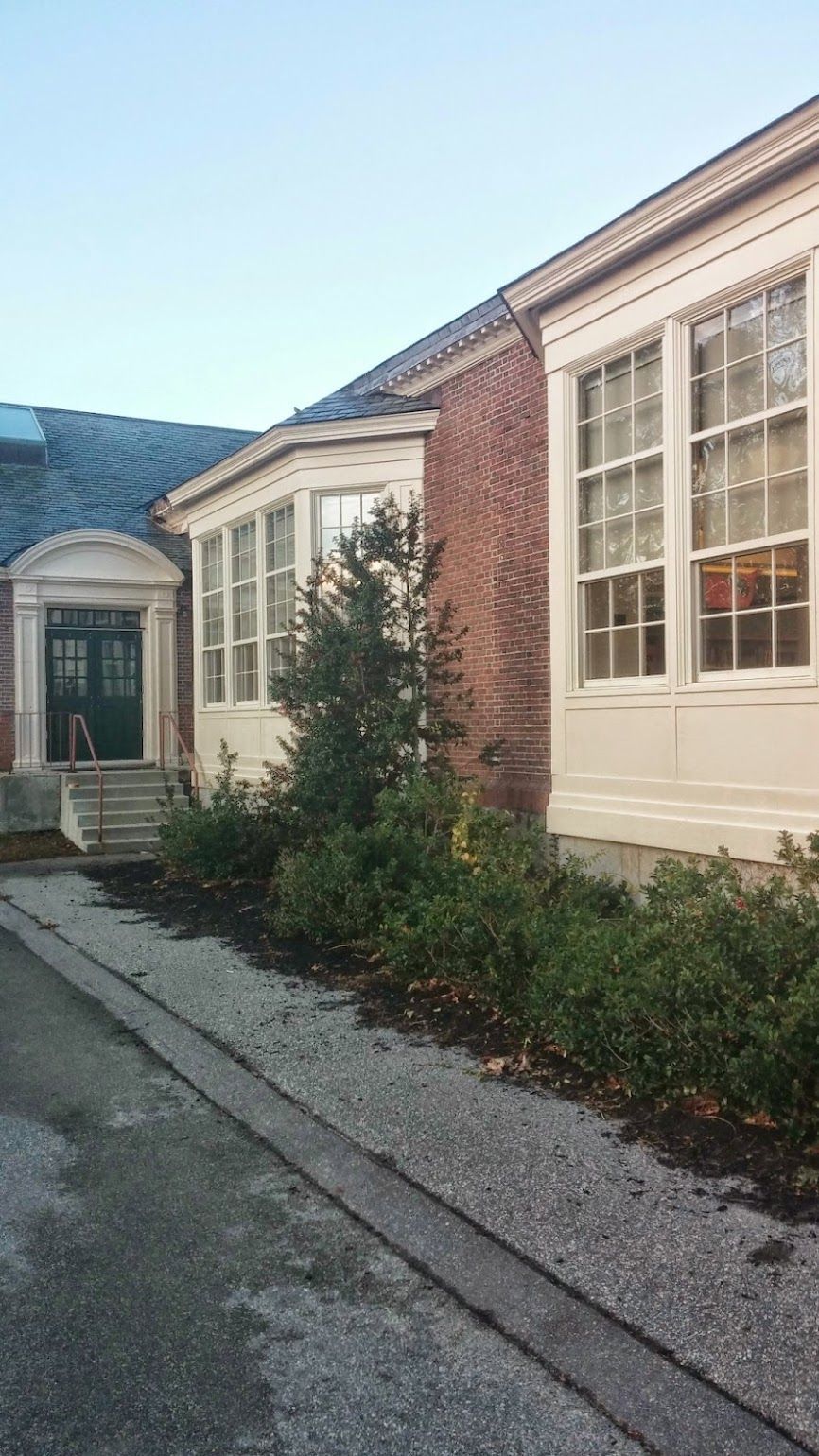 A large brick building with a lot of windows and bushes in front of it.