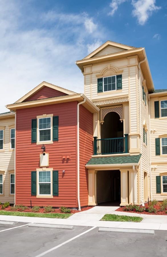 A large apartment building with red siding and green shutters