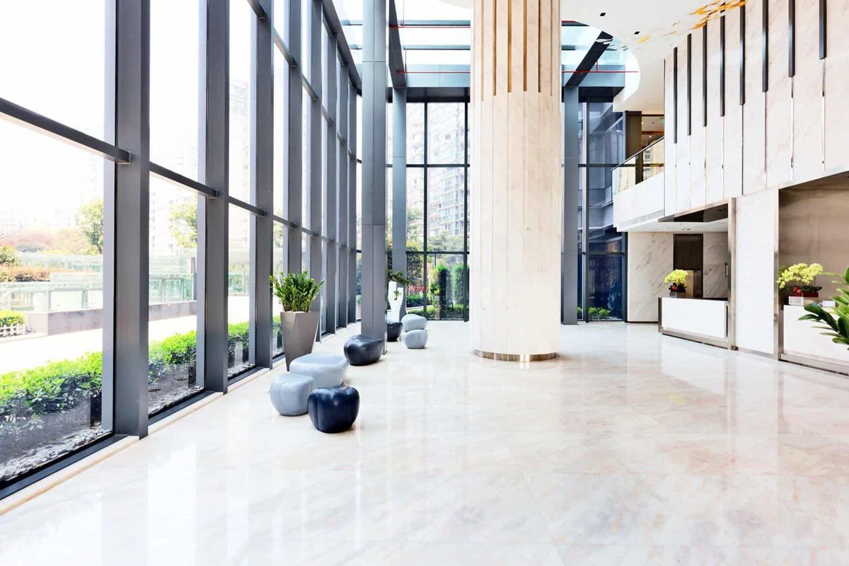 An empty lobby of a large building with lots of windows.
