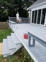 A man is painting the deck of a house.