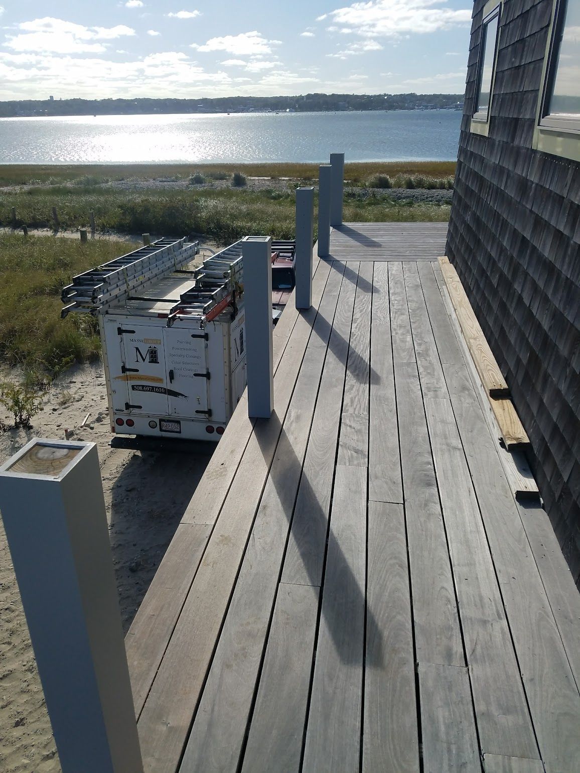 A white truck is parked on a wooden deck overlooking a body of water
