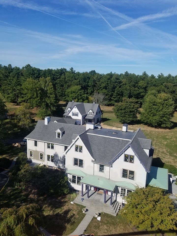 An aerial view of a large white house surrounded by trees.