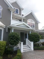 A large house with a white porch and stairs is being painted.