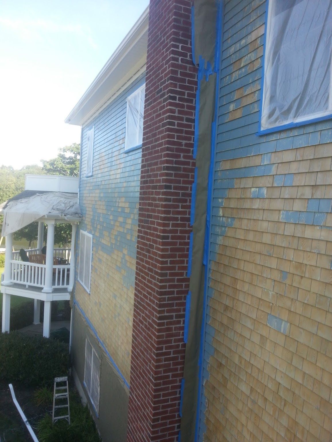 A house with a brick chimney is being painted blue