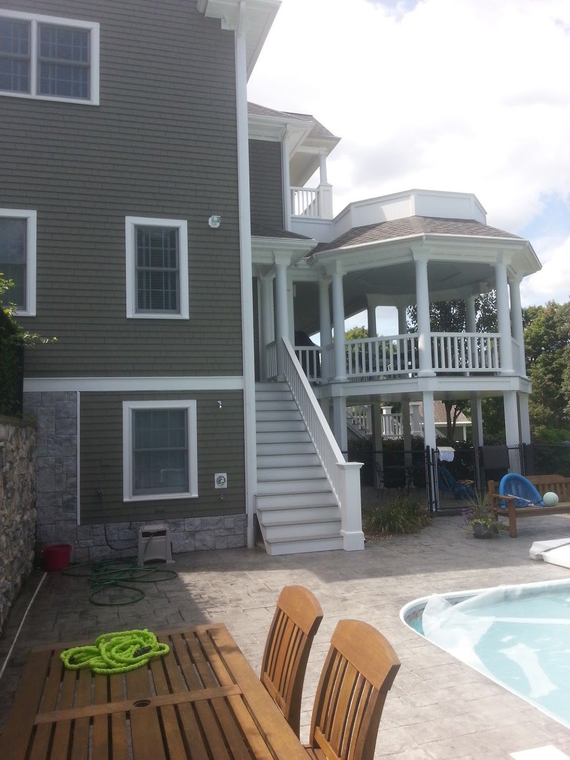A large house with a swimming pool and a table and chairs in front of it.