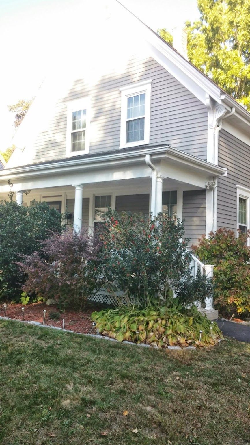A house with a porch and a lawn in front of it.