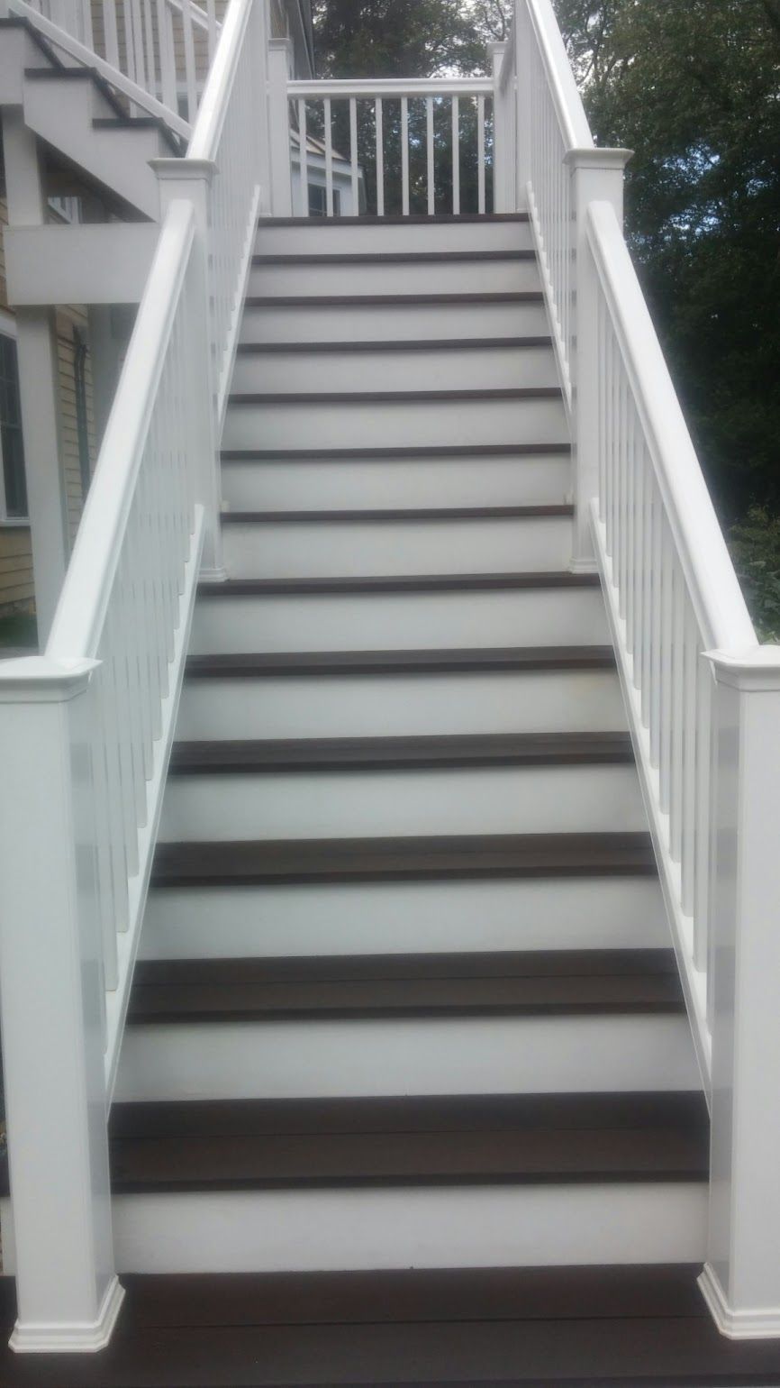 A set of stairs leading up to a deck with a white railing.