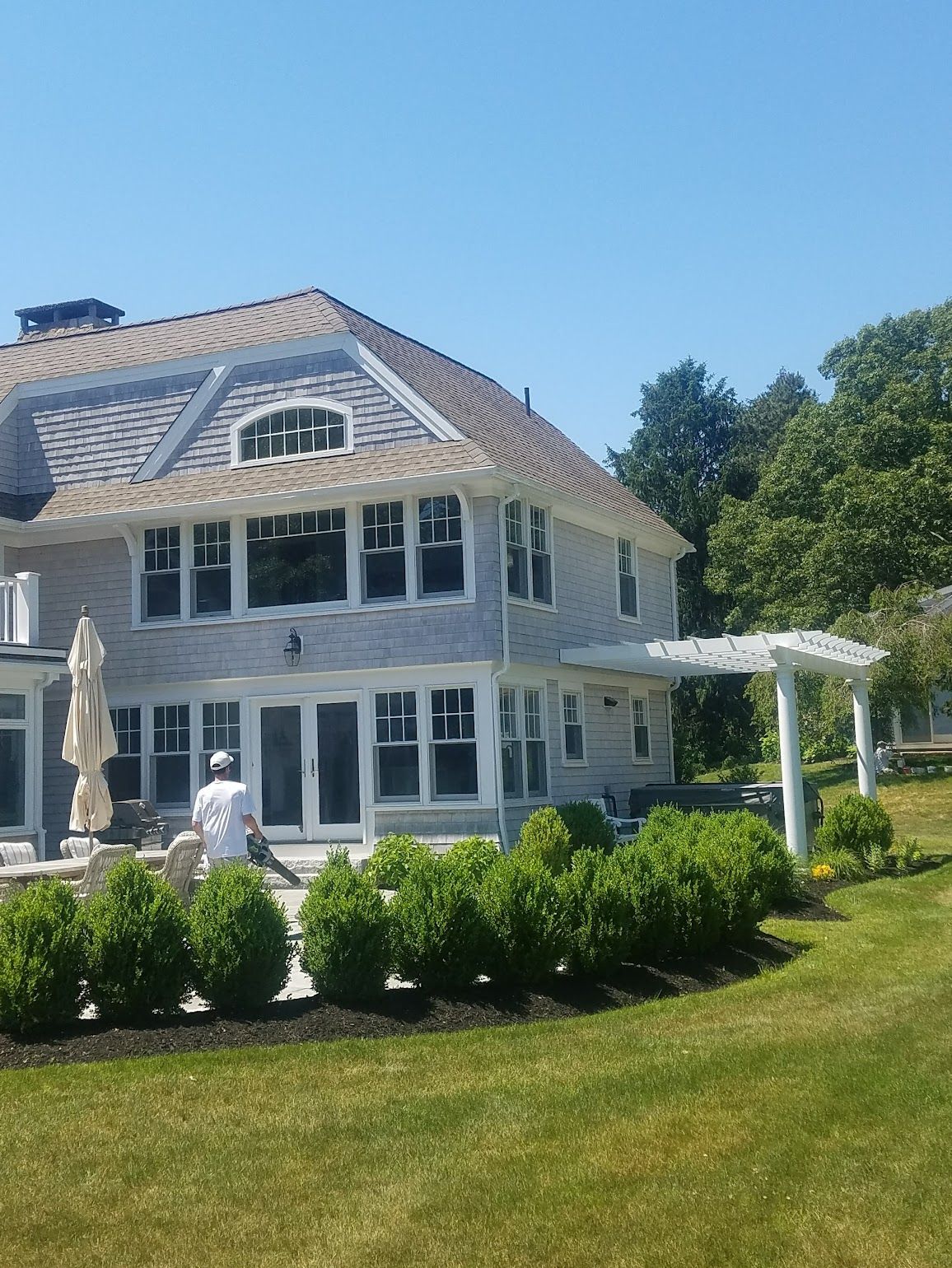 A large house with a lot of windows is surrounded by bushes and trees