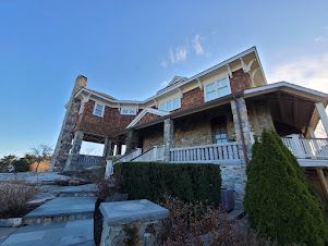 A large house with stairs leading up to it and a blue sky in the background.