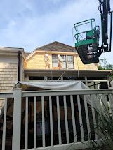 A man is painting the roof of a house with a crane.