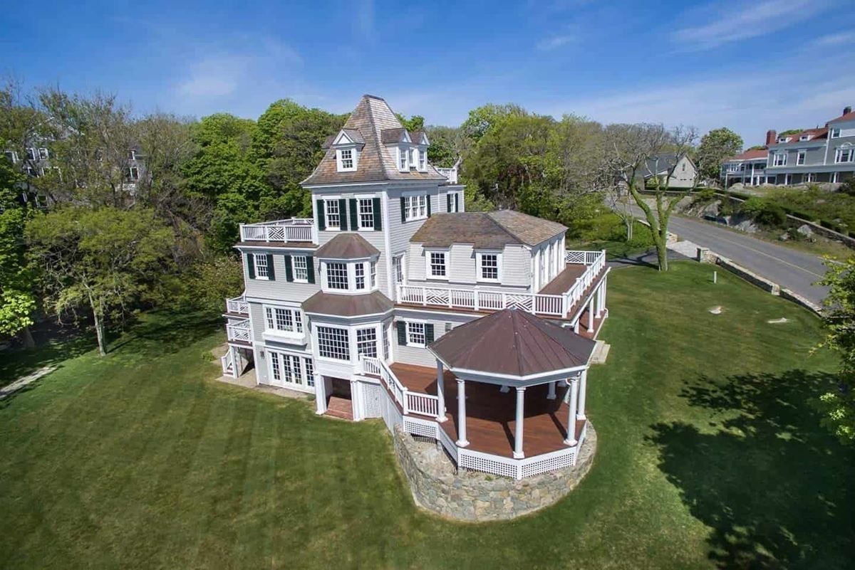 An aerial view of a large house with a gazebo in the middle of a lush green field.