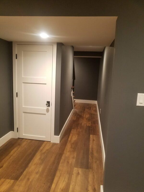 A hallway with wooden floors and a white door.