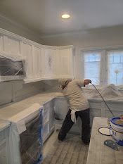 A man is painting a kitchen with a sprayer.