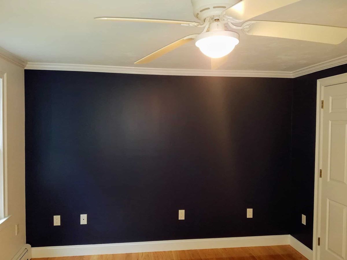 A room with dark blue walls and a ceiling fan