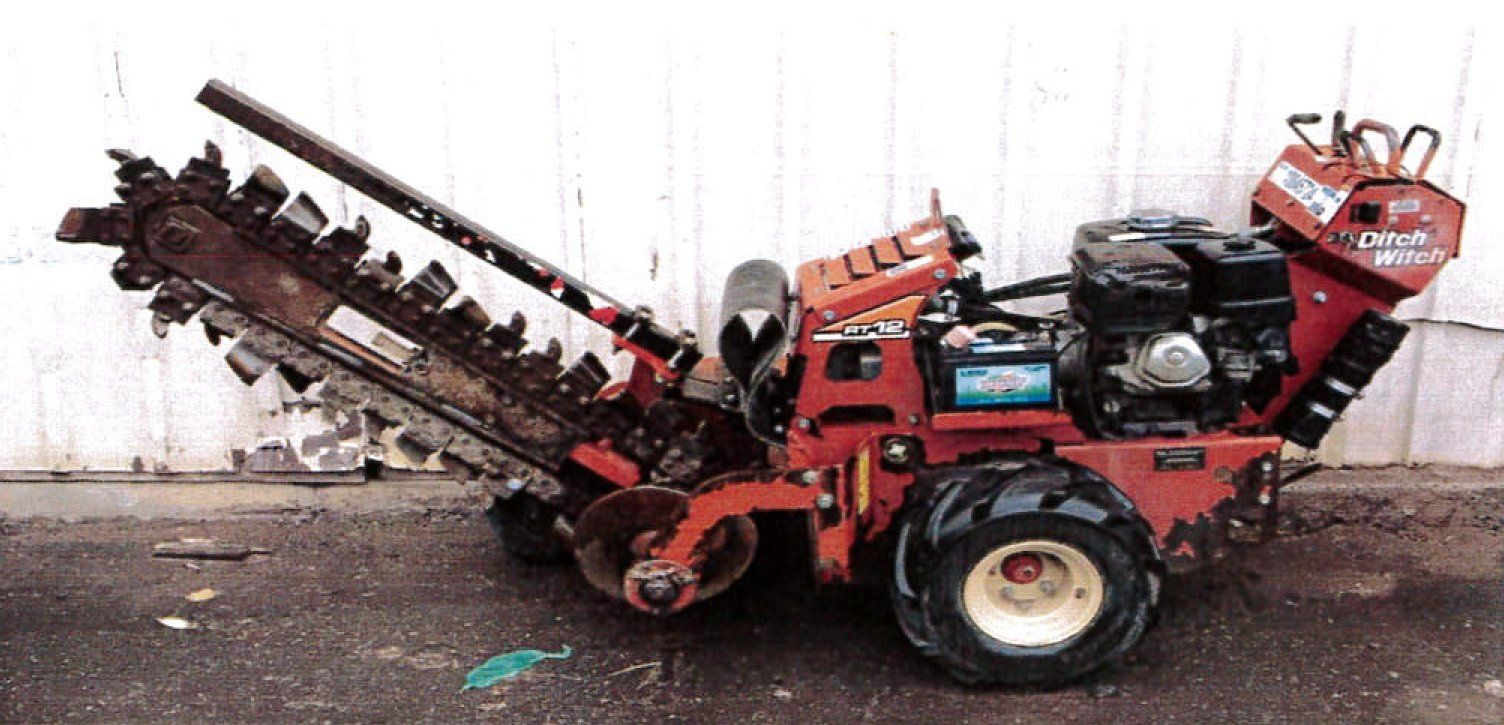Red Ditch Witch trencher parked on asphalt; against a white wall.