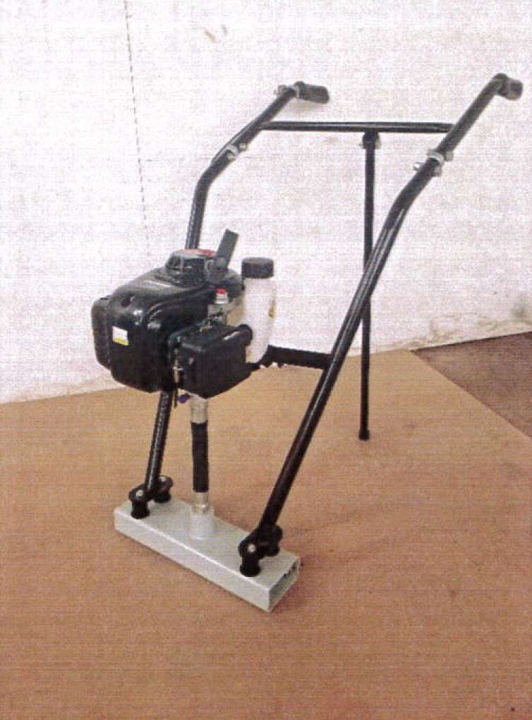 A black and silver gasoline-powered plate compactor on a wooden surface.