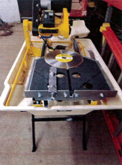 Yellow and black tile saw with a circular blade on a table.