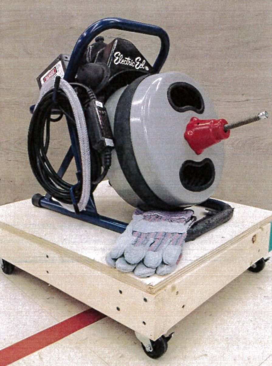 A drain cleaning machine on a wooden platform with gloves.