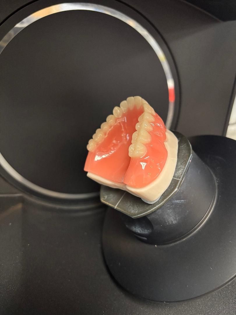 A partial Hypoallergenic dentures set resting on a dental scanner mount inside a laboratory scanner.