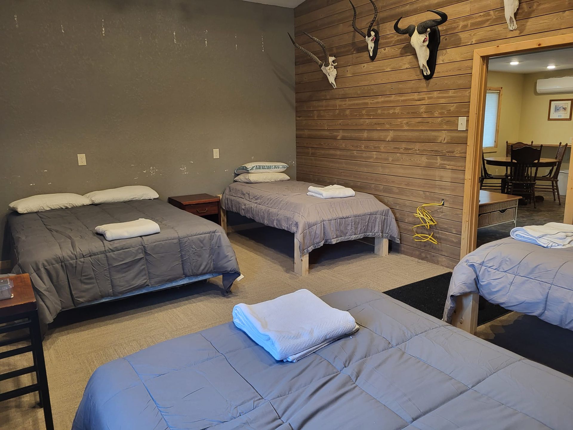 A bedroom with three beds and two skulls on the wall.