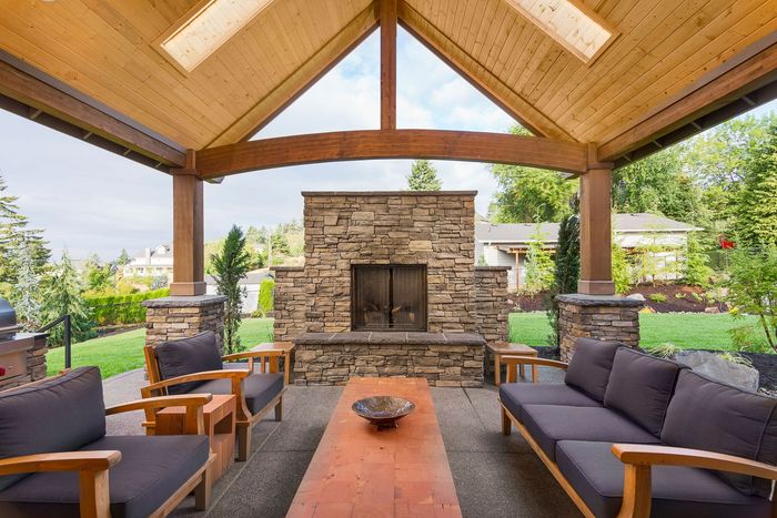 A patio with a couch , chairs , and a fireplace.