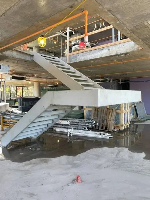 Concrete staircase under construction. Gray steps ascend from a flooded floor.