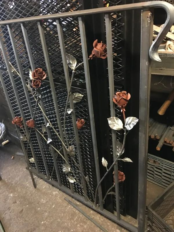 Metal gate with rose decorations; dark metal bars with copper and silver rose accents.