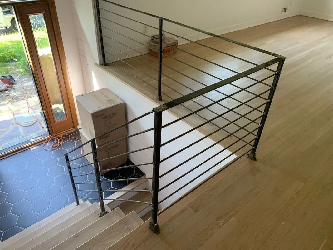 Interior view of staircase with black metal railing and wooden flooring.