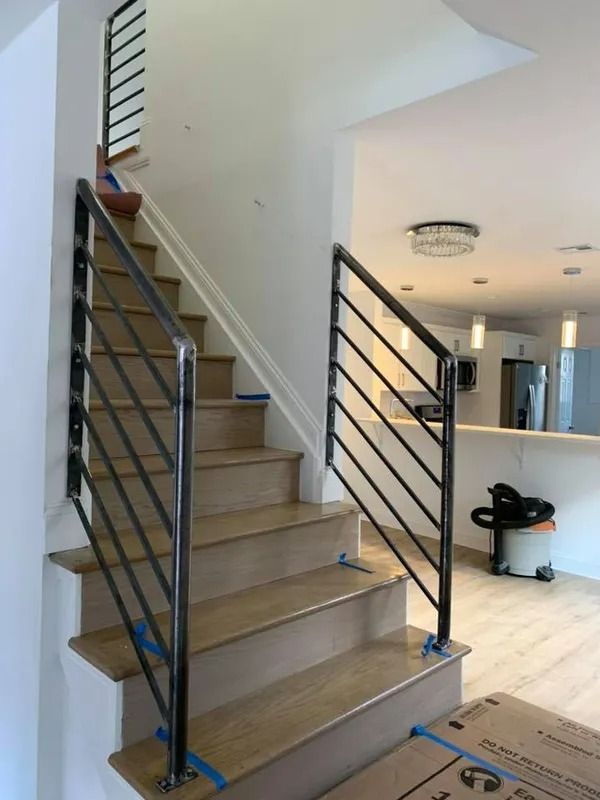 Staircase with wooden steps and black metal railing in a modern home.