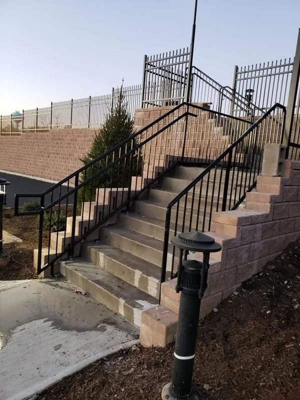 Staircase with black railings built into a retaining wall. A lamp post is in the foreground.