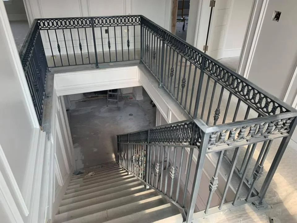 A staircase with gray metal railings, descending into a lower level with unfinished walls.