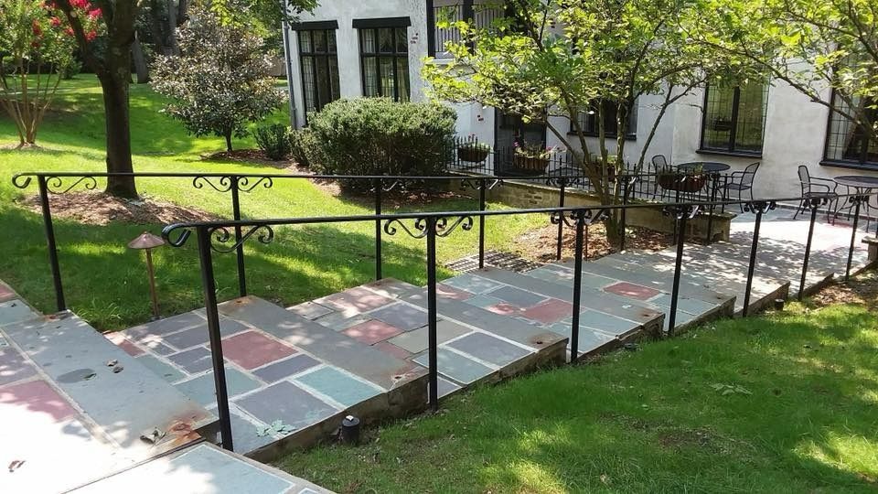 Exterior steps with black metal handrails leading to a white house with black windows.