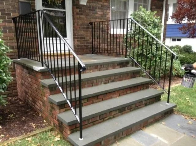 Brick steps leading up to a house with black metal railings.