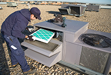 Worker changing a roof top air exchange units filter