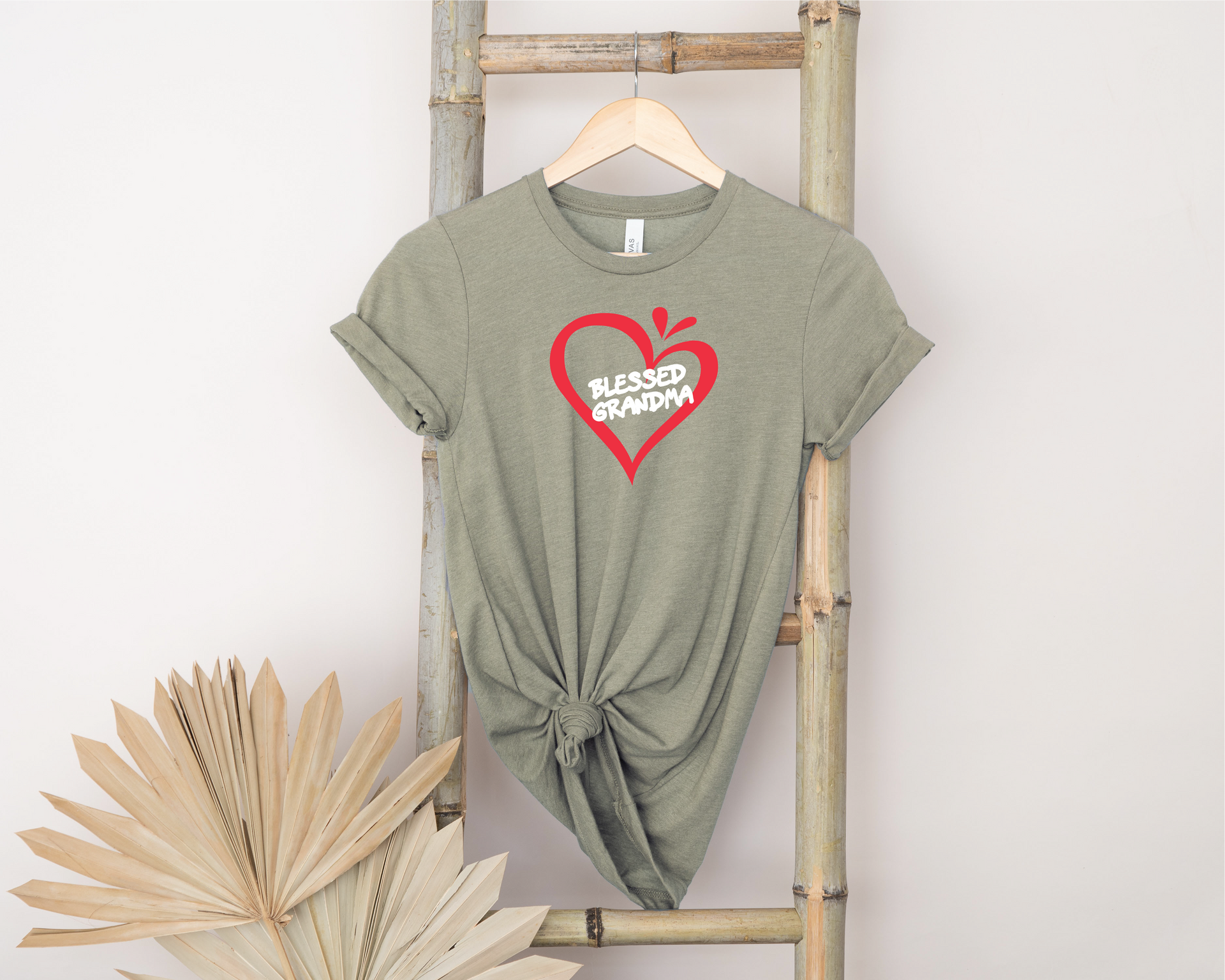 A t-shirt with a heart on it is hanging on a wooden ladder.