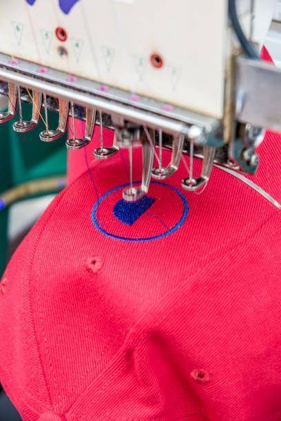A red hat is being embroidered with a blue circle.