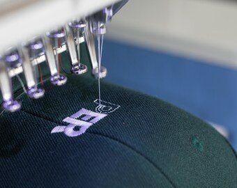 A close up of a hat being embroidered with a sewing machine.