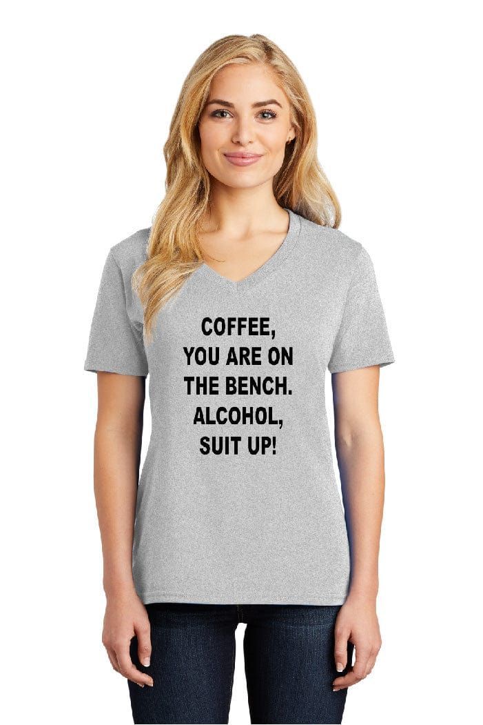 A woman is wearing a t-shirt that says coffee you are on the bench alcohol suit up