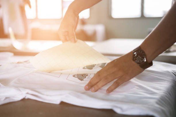 A person is holding a piece of paper over a white t-shirt.