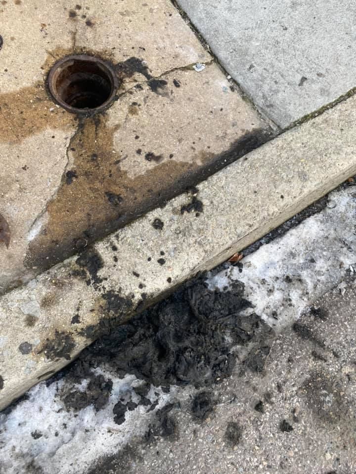 Sidewalk with a drain, dirty slush, and a curb.