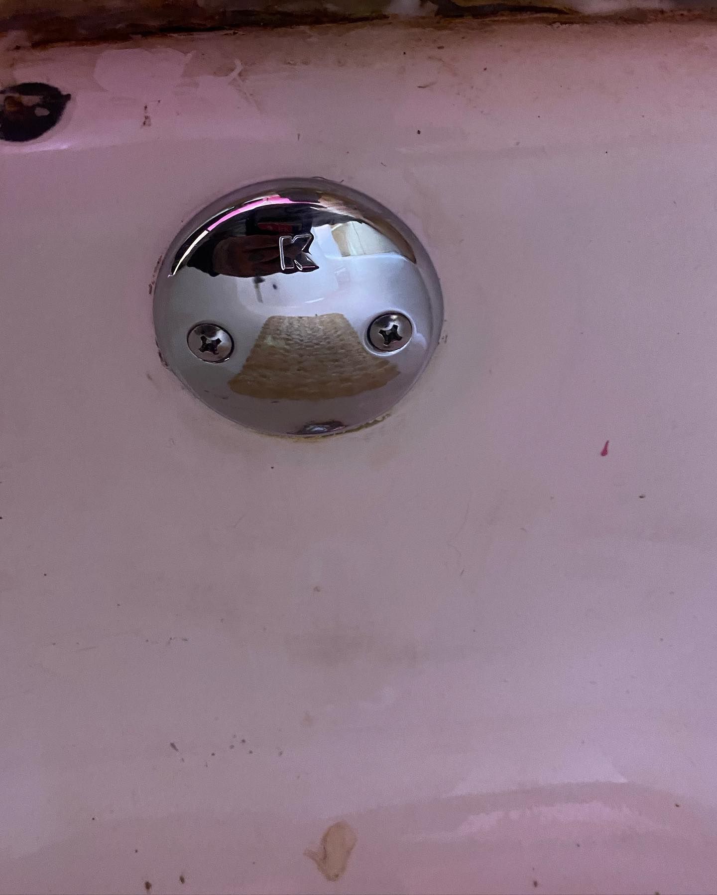 Chrome drain cover with screws on a white bathtub.