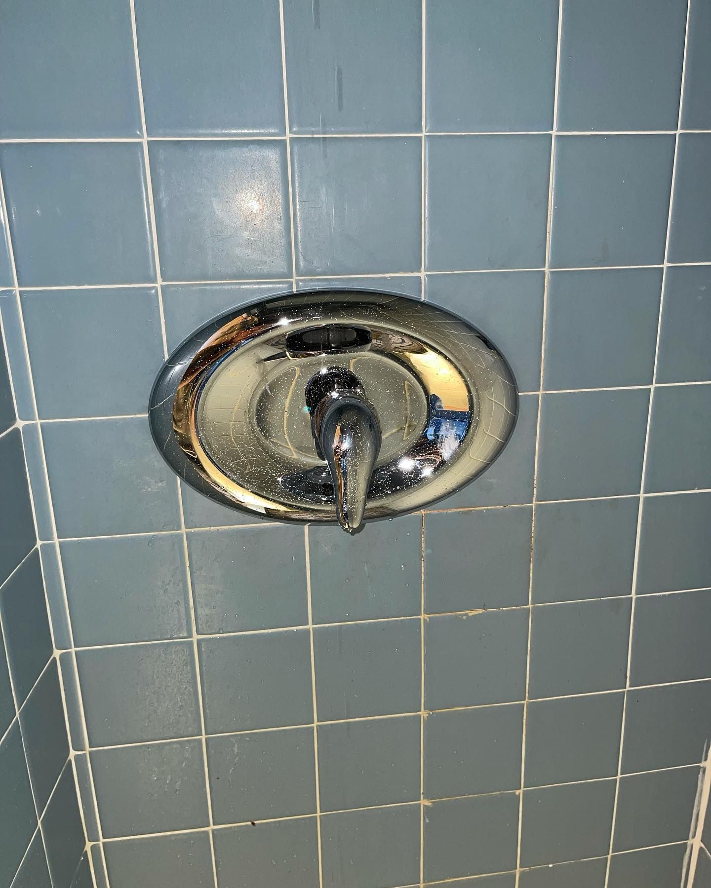 Chrome shower faucet on blue tile wall.