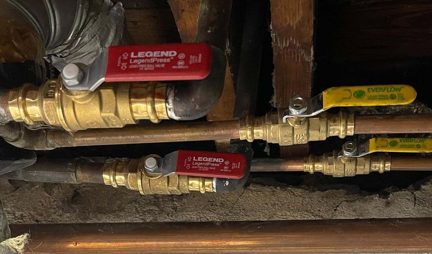 Brass and copper plumbing pipes with red and yellow valve handles.